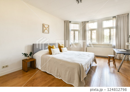 A bright and airy modern bedroom featuring a cozy bed, warm wooden flooring, and soft natural light streaming through the windows, enhancing its minimalist design. A bright and airy modern bedroom featuring a cozy bed, warm wooden flooring, and soft natural light streaming through the windows, enhancing its minimalist design. 124812798