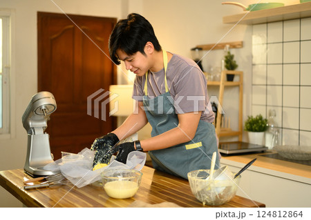 Young man in an apron preparing homemade butter in a modern kitchen 124812864