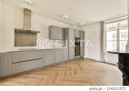 A sleek, modern kitchen featuring gray cabinetry, wooden flooring, and contemporary appliances, ideal for culinary enthusiasts and design lovers. 124812872