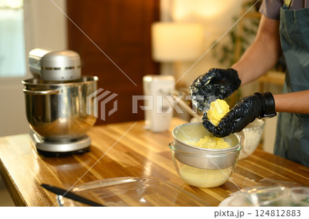 Man wearing black gloves squeezing out buttermilk from freshly churned butter 124812883