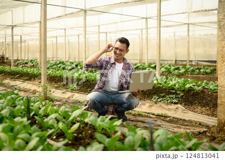 Smiling man using laptop for crop monitoring and digital farming records 124813041