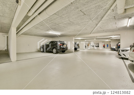 Spacious underground parking garage with bright lighting and a clean, minimalistic design. Ideal for vehicle storage and access. 124813082