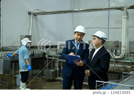 Factory supervisors in hard hats inspecting a production line in an industrial facility 124813085