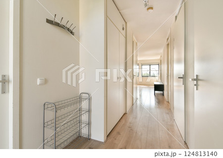 A spacious and modern hallway featuring minimalist decor, light-colored walls, and wooden flooring, complemented by natural light from large windows. A spacious and modern hallway featuring minimalist decor, light-colored walls, and wooden flooring, complemented by natural light from large windows. 124813140