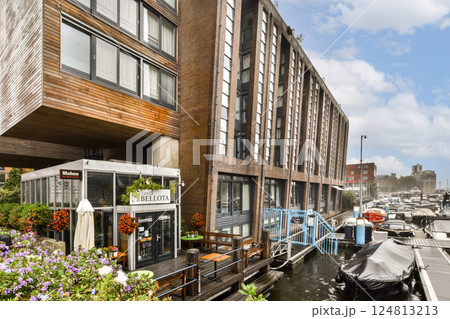 A striking modern building overlooking a waterfront with vibrant flowers in front, showcasing a blend of architecture and nature. A striking modern building overlooking a waterfront with vibrant flowers in front, showcasing a blend of architecture and nature. 124813213