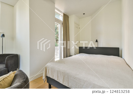 A serene minimalist interior featuring a soft bed, large windows allowing natural light, and simple furnishings, creating a calming atmosphere. A serene minimalist interior featuring a soft bed, large windows allowing natural light, and simple furnishings, creating a calming atmosphere. 124813258