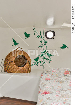 A charming bedroom featuring a floral bedspread, a wicker basket, and bird silhouettes on the wall, creating a serene and inviting atmosphere. 124813259