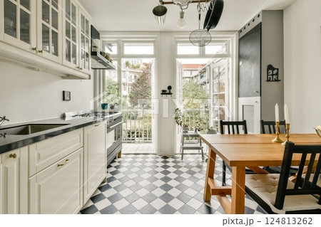 A stylish modern kitchen showcasing elegant cabinetry and a refined dining area, complemented by natural light and tasteful decor. 124813262