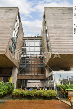 A contemporary building featuring a wooden exterior and large glass windows, surrounded by greenery, showcasing modern architectural trends. 124813276