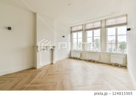 Spacious and well-lit modern room featuring large windows and elegant flooring. The minimalist design offers a fresh ambiance for various uses. 124813305