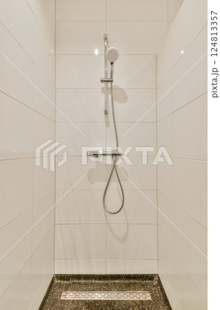 A sleek and minimalist shower setup featuring a modern showerhead and clean white tiles, creating a serene and elegant bathroom atmosphere. 124813357