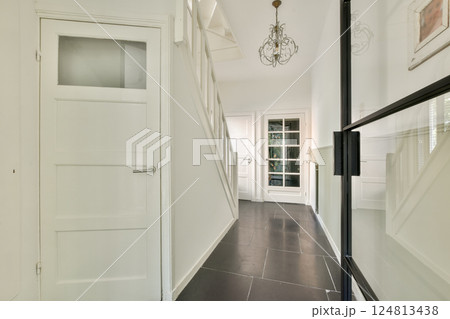 A sleek, modern interior hallway featuring a stylish chandelier, elegant flooring, and well-lit passageway that enhances the home's aesthetic appeal. A sleek, modern interior hallway featuring a stylish chandelier, elegant flooring, and well-lit passageway that enhances the home's aesthetic appeal. 124813438