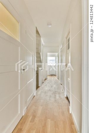 A bright and spacious interior hallway showcasing clean lines, white doors, and warm wood flooring, emphasizing contemporary design aesthetics. A bright and spacious interior hallway showcasing clean lines, white doors, and warm wood flooring, emphasizing contemporary design aesthetics. 124813442