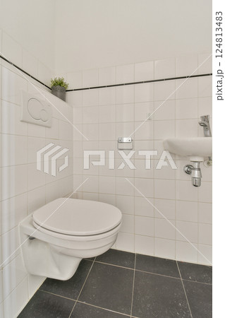 A clean and modern bathroom featuring a white toilet, sleek faucet, and tiled walls, emphasizing minimalist design principles and functionality. A clean and modern bathroom featuring a white toilet, sleek faucet, and tiled walls, emphasizing minimalist design principles and functionality. 124813483
