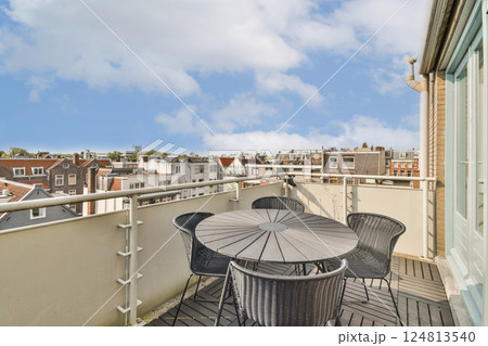 A scenic view from a rooftop terrace showcasing a round table surrounded by chairs, overlooking a bustling urban landscape under a blue sky. A scenic view from a rooftop terrace showcasing a round table surrounded by chairs, overlooking a bustling urban landscape under a blue sky. 124813540