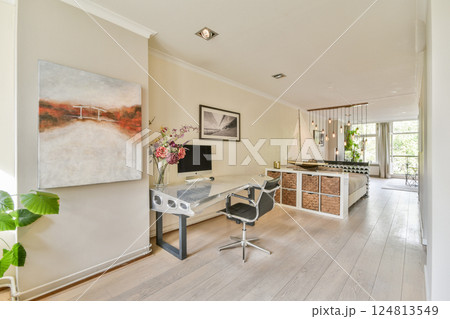 A bright and airy modern interior featuring a workspace, elegant decor, and a blend of neutral tones with natural light streaming through. 124813549