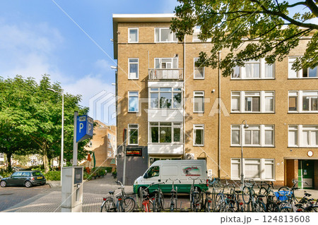A contemporary building features large windows and balconies, surrounded by trees and parked bicycles, measuring urban lifestyle and green living. A contemporary building features large windows and balconies, surrounded by trees and parked bicycles, measuring urban lifestyle and green living. 124813608