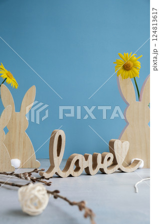 LOVE wooden word on festive blue background and eco-friendly zero waste natural decoration. Yellow daisies flowers. Bunny egg. Holiday greeting LOVE wooden word on festive blue background and eco-friendly zero waste natural decoration. Yellow daisies flowers. Bunny egg. Holiday greeting 124813617