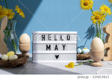 Phrase HELLO MAY traditional greeting to christian holiday. Festive mood composition with bunnies and yellow flowers on pastel blue background. Sustainable natural materials Phrase HELLO MAY traditional greeting to christian holiday. Festive mood composition with bunnies and yellow flowers on pastel blue background. Sustainable natural materials 124813621