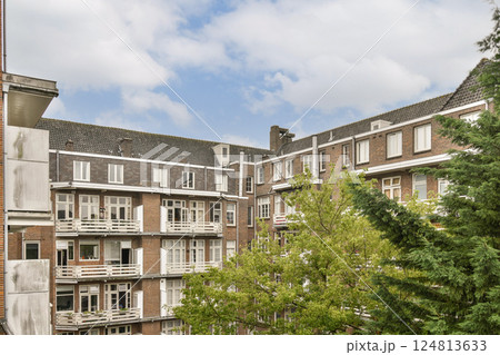 A contemporary apartment building showcasing modern architecture alongside lush greenery, providing a blend of urban living and nature. A contemporary apartment building showcasing modern architecture alongside lush greenery, providing a blend of urban living and nature. 124813633