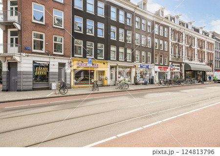 A picturesque Amsterdam street featuring traditional architecture, vibrant shops, and bicycles lining the pathways beneath a clear blue sky. A picturesque Amsterdam street featuring traditional architecture, vibrant shops, and bicycles lining the pathways beneath a clear blue sky. 124813796