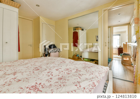 A bright and inviting bedroom showcasing a floral-patterned bedspread, minimalist furniture, and warm tones, perfect for relaxation and comfort. A bright and inviting bedroom showcasing a floral-patterned bedspread, minimalist furniture, and warm tones, perfect for relaxation and comfort. 124813810