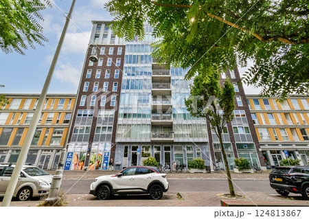Contemporary architecture showcases a modern apartment building surrounded by trees and urban elements, blending nature with city life. Contemporary architecture showcases a modern apartment building surrounded by trees and urban elements, blending nature with city life. 124813867