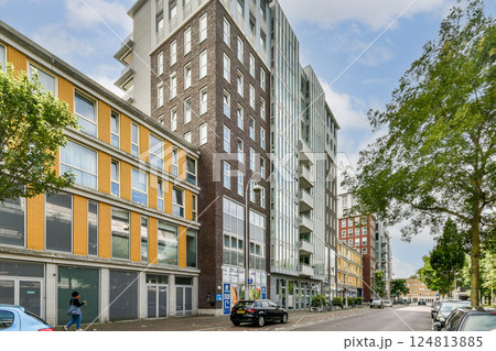 A view of contemporary buildings showcasing a blend of styles, with vibrant facades and greenery along the street, reflecting city urbanization. 124813885