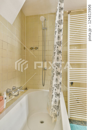 A clean and functional bathroom featuring a bathtub, showerhead, and tiled walls. The space radiates simplicity and practicality for everyday use. A clean and functional bathroom featuring a bathtub, showerhead, and tiled walls. The space radiates simplicity and practicality for everyday use. 124813906