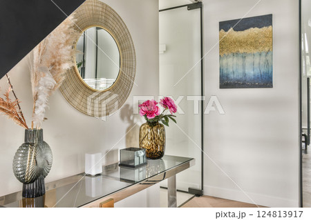 A stylish modern interior featuring a decorative mirror, floral arrangements, and contemporary artwork that enhances the overall ambiance of the space. 124813917