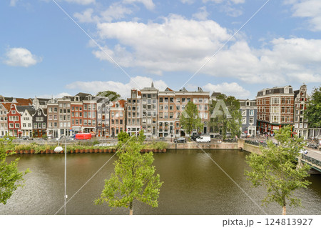 A beautiful view of a riverfront lined with historic buildings and lush greenery under a blue sky, showcasing architectural diversity and natural beauty. A beautiful view of a riverfront lined with historic buildings and lush greenery under a blue sky, showcasing architectural diversity and natural beauty. 124813927
