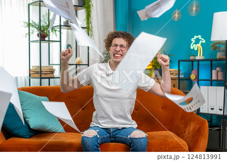 Stressed man freelancer reviewing business charts and graphs and throwing papers unpaid bills in air 124813991