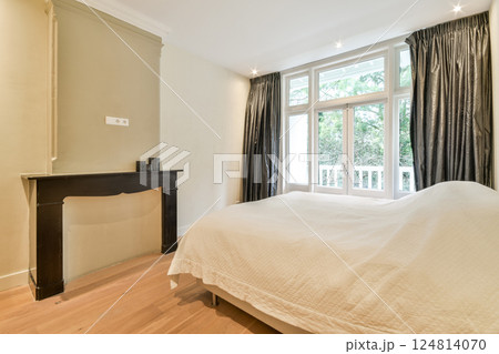 A serene bedroom featuring light-colored walls, a soft bed, and large windows allowing natural light to fill the space, creating a warm atmosphere. A serene bedroom featuring light-colored walls, a soft bed, and large windows allowing natural light to fill the space, creating a warm atmosphere. 124814070