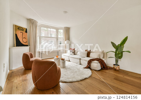 A stylish and inviting modern living room with a warm color palette featuring a comfortable sofa, unique decor, and a touch of greenery. 124814156