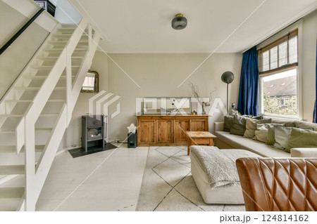 A spacious and stylish living room featuring a comfortable sofa, elegant furniture, and contemporary decor. The room showcases warm lighting and inviting atmosphere. A spacious and stylish living room featuring a comfortable sofa, elegant furniture, and contemporary decor. The room showcases warm lighting and inviting atmosphere. 124814162