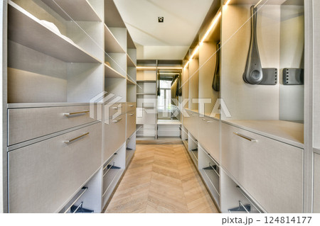 A sleek, modern walk-in closet featuring ample shelving and soft lighting, creating an organized space for clothing and accessories. 124814177