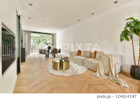A stylish modern living room featuring elegant furniture, a plush rug, a dining area, and large windows allowing natural light to fill the space. A stylish modern living room featuring elegant furniture, a plush rug, a dining area, and large windows allowing natural light to fill the space. 124814197