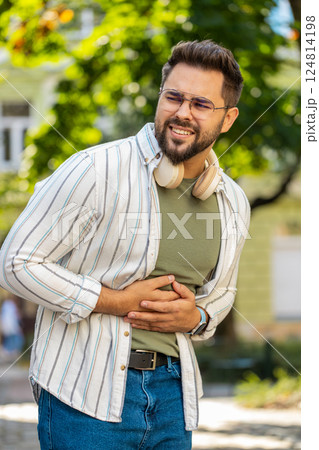 Caucasian young man traveler feeling sudden strong abdominal stomach pain problem on city street 124814198