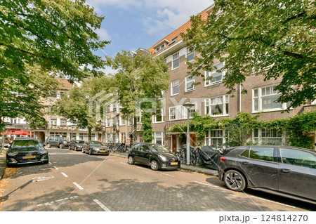 A picturesque view of a residential street lined with trees and parked cars. The buildings feature a blend of modern and traditional architecture, enhancing the local charm. A picturesque view of a residential street lined with trees and parked cars. The buildings feature a blend of modern and traditional architecture, enhancing the local charm. 124814270