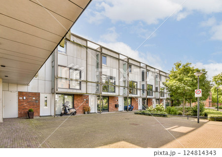 Contemporary residential buildings feature a clean design complemented by lush greenery and well-maintained walkways, showcasing urban living in harmony with nature. 124814343