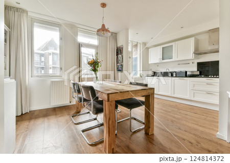 A bright and airy modern dining area featuring a wooden table, stylish chairs, and large windows bringing in ample natural light, creating an inviting atmosphere. A bright and airy modern dining area featuring a wooden table, stylish chairs, and large windows bringing in ample natural light, creating an inviting atmosphere. 124814372