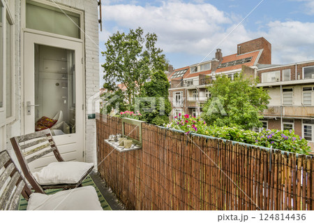 A cozy balcony adorned with plants and flowers, providing a serene escape in an urban setting. The view offers a blend of nature and city architecture. A cozy balcony adorned with plants and flowers, providing a serene escape in an urban setting. The view offers a blend of nature and city architecture. 124814436