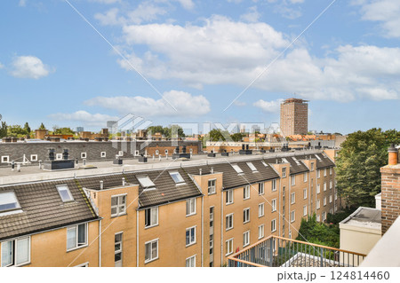 A captivating view of urban rooftops and buildings bathed in natural light under a clear sky. The cityscape showcases architectural diversity and greenery. 124814460