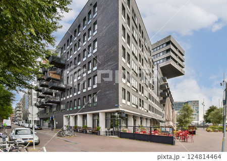 A contemporary building featuring unique angles, large windows, and a stylish outdoor seating area in an urban setting. 124814464