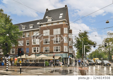 This image captures a bustling city intersection showcasing striking historical architecture under a partly cloudy sky, with pedestrians and traffic in view. This image captures a bustling city intersection showcasing striking historical architecture under a partly cloudy sky, with pedestrians and traffic in view. 124814508