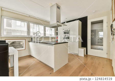 A sleek and contemporary kitchen featuring a minimalist design with elegant cabinets, modern appliances, and natural wood flooring, creating a warm ambiance. A sleek and contemporary kitchen featuring a minimalist design with elegant cabinets, modern appliances, and natural wood flooring, creating a warm ambiance. 124814519