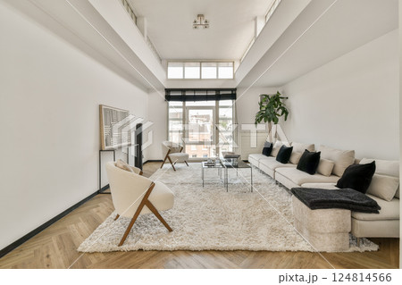 A spacious modern living room featuring a cozy white sofa, stylish decor, and large windows that flood the area with natural light. A spacious modern living room featuring a cozy white sofa, stylish decor, and large windows that flood the area with natural light. 124814566