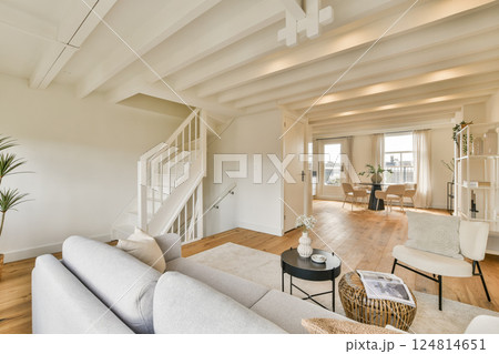 A stylish modern interior featuring a bright living room with a cozy sofa and a staircase leading to an upper level, blending comfort and elegance. A stylish modern interior featuring a bright living room with a cozy sofa and a staircase leading to an upper level, blending comfort and elegance. 124814651