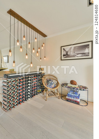 A stylish interior featuring elegant lighting fixtures, a wine rack, comfortable seating, and decorative elements, creating an inviting and modern atmosphere. 124814680