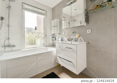 A sleek and contemporary bathroom featuring a bathtub, modern fixtures, and natural light streaming through the window, creating a serene atmosphere. A sleek and contemporary bathroom featuring a bathtub, modern fixtures, and natural light streaming through the window, creating a serene atmosphere. 124814819